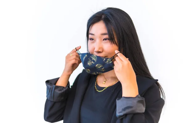 Young Asian girl in a black jacket putting on face mask with white background, new normal, social distance. Girl born in Wuhan city in china, coronavirus, covid-19