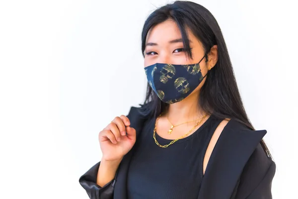 Young Asian girl wearing a black jacket smiling and face mask with white background, new normal, social distance. China born in Wuhan city in china, coronavirus, covid-19