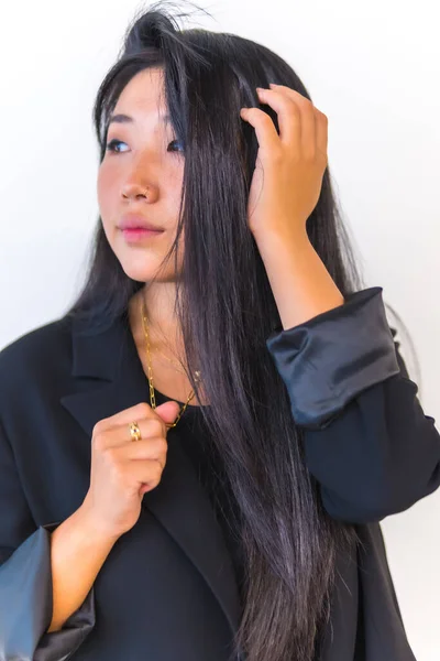 Young Asian girl wearing a black jacket and looking sideways smiling against white background. Lifestyle of young girl of Chinese nationality