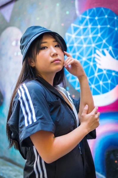 年轻的亚洲女孩 戴着黑色的帽子 身穿黑色的连衣裙 背景是粉红的城市图画 与一名中国裔青年妇女在城市举行的会议 — 图库照片