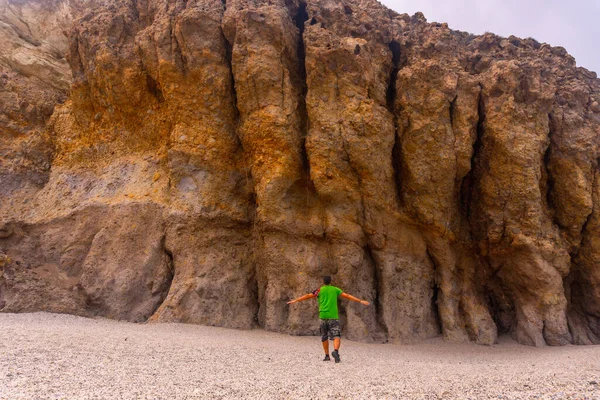 A young man with open arms in the beautiful natural walls of Playa de los Muertos in the natural park of Cabo de Gata, Nijar, Andalucia. Spain