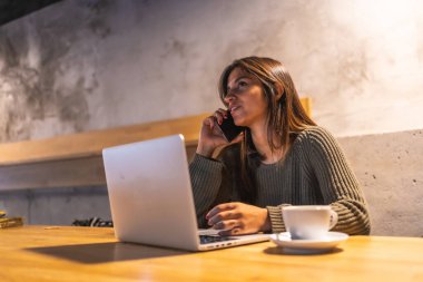 Kafkasyalı genç bir esmer girişimci bir kafede çalışıyor. Kahve içmek, telefonla konuşmak ve bilgisayarda çalışmak.
