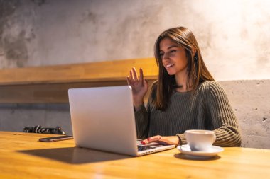 Kafkasyalı genç bir esmer girişimci bir kafede çalışıyor. Kahve içip bilgisayarla video görüşmesi yapıyorum.