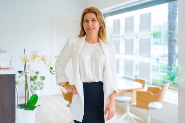 Ofiste gururla duran şık bir emlakçının yatay portresi.