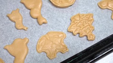 Kardan adam, ren geyiği ve ağaç şeklinde Noel kurabiyeleri, parşömen tepsisinde altın rengi kahverengi, bayram sıcaklığı yayıyor.