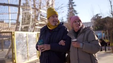 Kıdemli çift birlikte yürüyor, neşeli noel şehir dekorasyonları arasında sıcak sohbetler yapıyorlar, sevgi ve aktif emeklilik yaşam tarzlarını ifade ediyorlar.