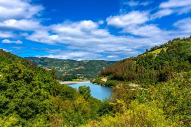 Bereketli bir mavi gökyüzü ve tüylü beyaz bulutların bulunduğu Bask ülkesindeki Tolosa 'nın gür tepelerinin arasında yuva yapmış huzurlu ibiur rezervuarı doğal huzuru somutlaştırıyor.