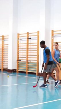 Profesyonel hokey oyuncuları kapalı bir spor salonunda top sürme ve sopa tutma teknikleri uyguluyor, bir antrenman sırasında bireysel beceriler ve takım koordinasyonu sergiliyorlar.