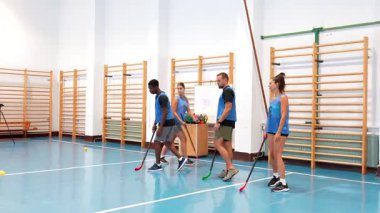 Çok kültürlü zemin topu ekibi, profesyonel iç saha spor tesisi içinde yoğun pas, atış ve stratejik takım talimleri yoluyla kolektif beceriler geliştiriyor.