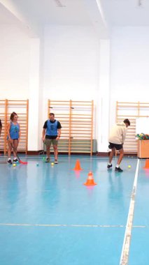 Profesyonel florbol oyuncuları, bir spor salonunda yoğun bir eğitim sırasında, çevikliklerini ve takım çalışmalarını göstermek için top sürme becerileri ve pas teknikleri üzerinde çalışırlar.