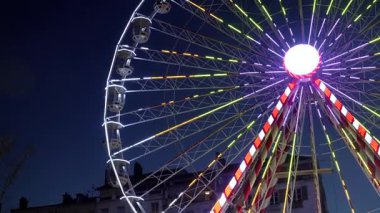 Bayonne 'da gece karanlığında dönen hareketli dönme dolap. Çok renkli ışıklar, Fransa 'da Noel kutlamalarının özünü yansıtan neşeli bir atmosfer yaratıyor.
