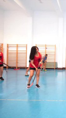 Genç sporcular yoğun zemin topu maçında yarışıyor, top atarken takım çalışması ve beceri sergiliyor ve dinamik enerji ve atletik hassasiyetle spor salonundaki golü hedefliyorlar.