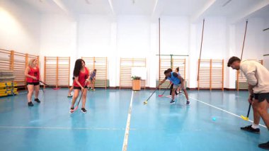 Kaliteli florbol sporcuları yoğun atışlar ve hassas paslar yapıyor, kapalı spor tesislerindeki yüksek enerji antrenmanı sırasında güçlü takım çalışması ve koordinasyon gösteriyorlar.