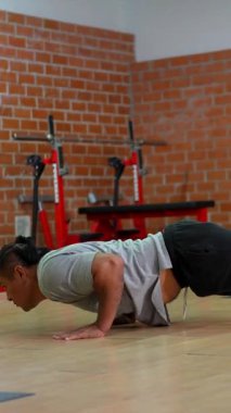 Kas özürlü atlet, protez bacaklı, şınav çeken, ayakta duran, inanılmaz bir güç, azim ve adaptif antrenman sergileyen zorlu bir spor salonunda.