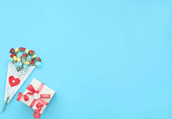 El ramo de flores artesanales envuelto en un paquete de encaje blanco y caja de regalo con cinta roja sobre fondo azul. Día de la madre, San Valentín, Boda, Concepto de cumpleaños. Tarjeta de felicitación. Estilo laico plano . — Foto de Stock