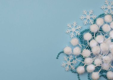 Noel süslemeleri ve beyaz kar taneleri olan mavi bir arka plan. Yeni yıl tebrik kartı. Düzleştirme biçimi.