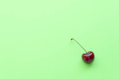 Yeşil arka planda taze kiraz. Sağlıklı beslenme, minimalizm kavramları. Metnin için kopyalama alanı olan düz konum biçimi.