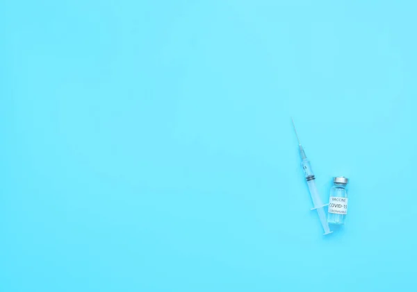 Fiala con vaccino contro il coronavirus e la siringa su fondo blu. Biohazard, 2019-nCoV, COVID-19. Il concetto di fine della pandemia, isolamento e quarantena. Posa piatta con spazio di copia, banner — Foto Stock