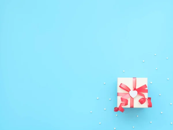 Weiße Geschenkbox mit roter Schleife und weißem Herz auf blauem Hintergrund mit Perlen. Muttertag, Valentinstag, Hochzeit, Geburtstag. Gruß- oder Einladungskarte. Flacher Lay-Stil mit Kopierraum. — Stockfoto