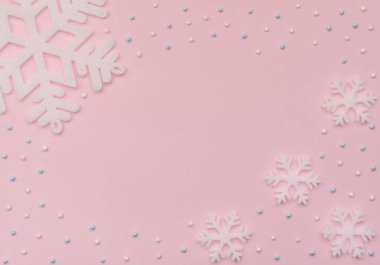 Christmas pink background with white snowflakes and beads. New Year greeting card. Flat lay style.	