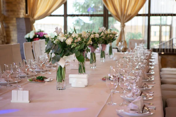 Wedding table decorated with flowers. Table setting for a banquet before the meal. Beautiful table setting on a holiday.