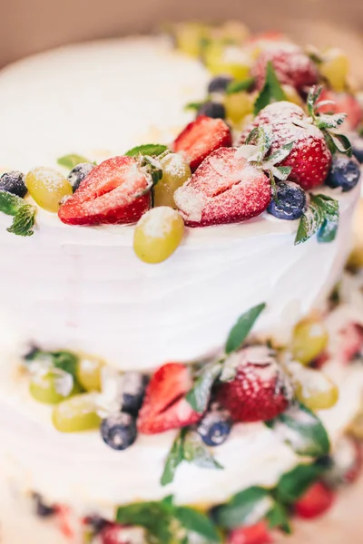 Three parts naked wedding cake with fruits and berries. White wedding cake with strawberries and berries.