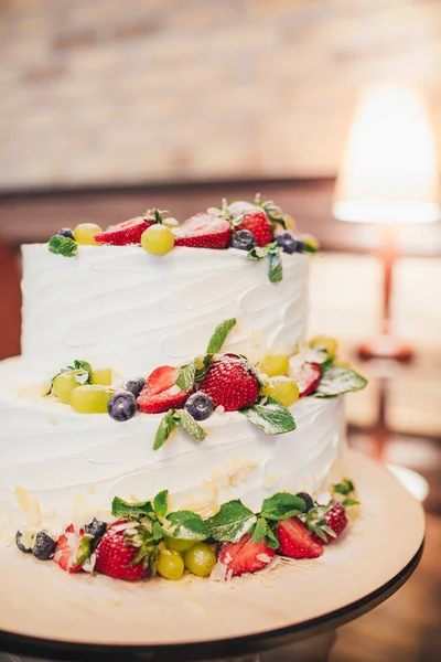 Three parts naked wedding cake with fruits and berries. White wedding cake with strawberries and berries.