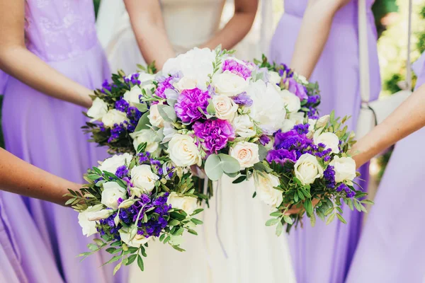 A noiva e damas de honra estão segurando buquês de flores . — Fotografia de Stock