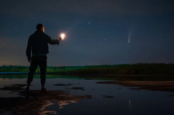 man with a lantern in the dark watches the starry sky