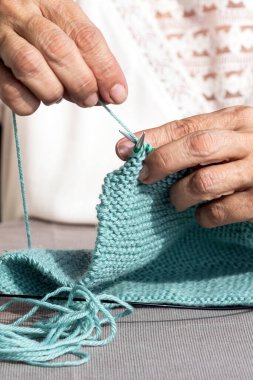 Dairesel iğneler kullanarak örgü ören ellerin yakın çekimi.