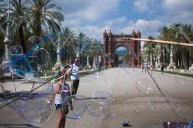 Barselona, İspanya - 8 Eylül 2014: Yayalar, Barselona, İspanya, Avrupa'da bulunan muhteşem Arc de Triomf'un önünde sabun kabarcıklarıyla oynuyor