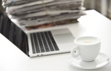 Bir mola konsepti fotoğrafı çek, gazete yığını, dizüstü bilgisayar ve bir fincan kahve aç.