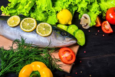 Çiğ taze balık ve malzemeler: limon, baharat, yeşillik, domates, ahşap bir masa, üstten görünüm üzerinde. Deniz Balık hazırlanması.
