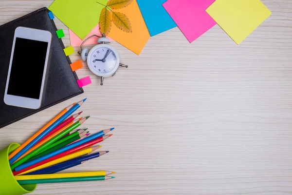 Okul kırtasiye masa üstü görünümünde kümesi. Renk kağıt, kalem, ahşap bir masa, boş alan smartphone.