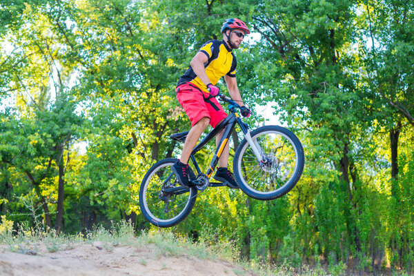 The concept of extreme cycling, a mountain bike jump. Enduro is a biker in a bright yellow T-shirt.