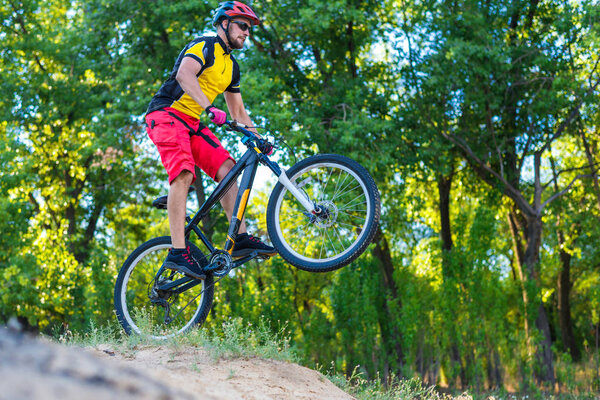 ?yclist in a yellow bright T-shirt is riding from the top, an active lifestyle. Professional enduro cyclist, mtb.