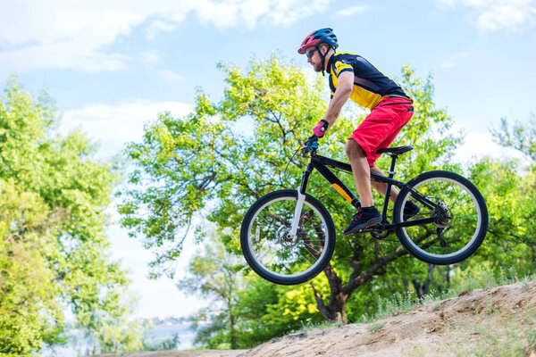 The concept of extreme cycling, a mountain bike jump. Enduro is a biker in a bright yellow T-shirt.