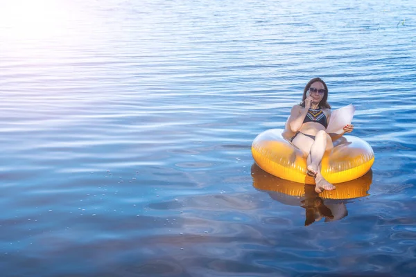 Tatil sırasında çalışma işkolik bir kadındır. Denizde şişme ringde siting ve Evet, iş kadını boş alan.