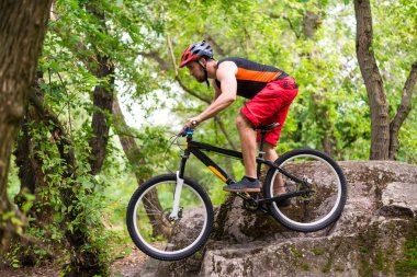 Bisiklete binme, bir dağ bisikleti üzerinde atlama bir bisikletçi aşırı. Bisikletçi bir boş alan bir güzel yaz ormandaki bir dağ bisikleti binme.