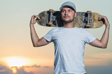 Parlak bir gün batımı arka planda şık bir kaykaycı portresi. Aktif yaşam tarzı.