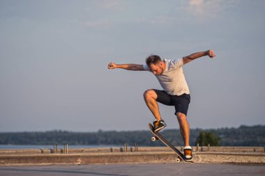 Mavi gökyüzü arka plan üzerinde bir ollie hile yaparak kaykaycı. Aktif yaşam tarzı.