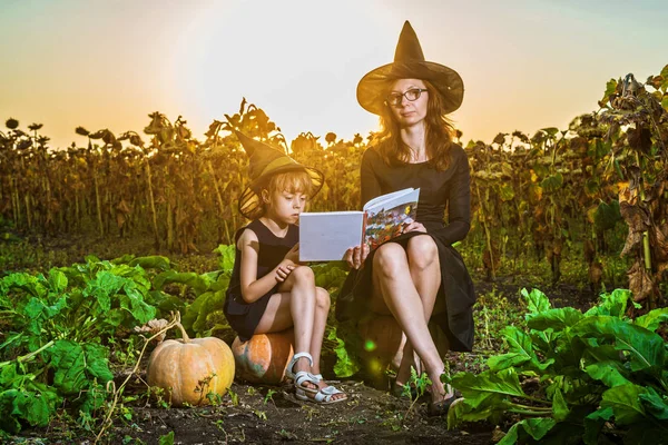 Мама Дочь Костюмах Ведьмы Сидят Тыквах Читают Книгу Концепцию Хэллоуина — стоковое фото