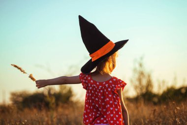 Çocuk cadı şapka açık havada, dikiz, kartpostal sonbahar tatil Cadılar Bayramı için. Bir cadı kostümü, muhteşem arka plan, küçük kız.