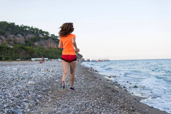 Active lifestyle: a slim woman runs along the beach.