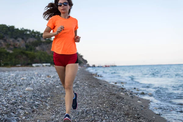 Active lifestyle: a slim woman runs along the beach.