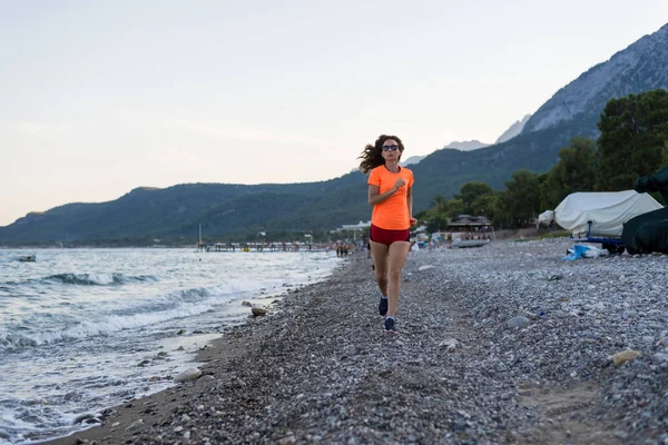 Estilo de vida activo: una mujer delgada corriendo por la playa . — Foto de Stock
