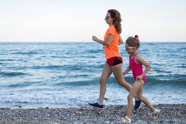 Active lifestyle: morning jogging along the beach. Mom and daugh