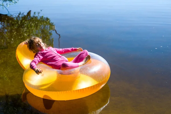 La niña está descansando en una silla inflable, flotando en el agua . — Foto de Stock