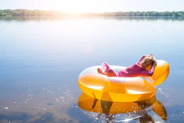 Den lilla flickan vilar i en uppblåsbar stol, flyter på vattnet. — Stockfoto