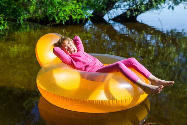 Niña se relaja en una silla inflable, flotando en el agua . — Foto de Stock